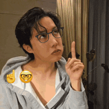a man wearing glasses and a hoodie is pointing up