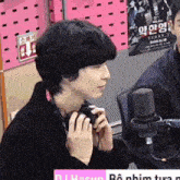 a man wearing headphones is talking into a microphone in front of a sign that says ' dj hasun '