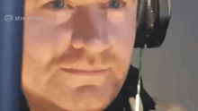 a man wearing headphones is making a funny face while looking at the camera .