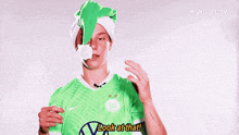 a soccer player wearing a green shirt and a santa hat says " look at that "