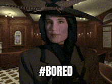 a woman wearing a hooded jacket and a hat with the hashtag #bored
