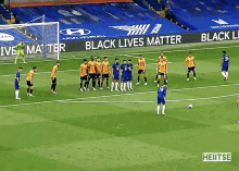 a group of soccer players stand on a field with a black lives matter banner behind them