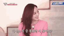 a woman in a pink top is smiling in front of a sign that says ' a ' on it