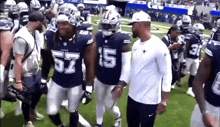 a group of football players are walking on a field and one of them is wearing a number 57 jersey .