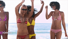 a group of women in bikinis are dancing on a beach with the number 142888494 in the corner