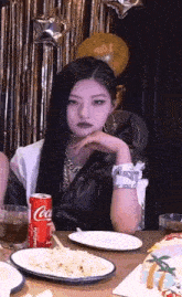 a woman is sitting at a table with a can of coca cola in her hand .