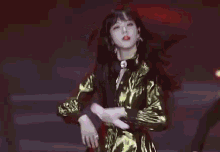 a woman in a gold dress is dancing on a stage .