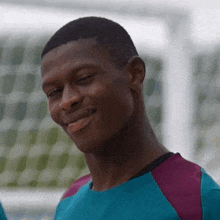 a man in a blue and purple shirt is smiling with his eyes closed