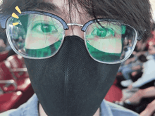 a person wearing glasses and a mask looks at the camera