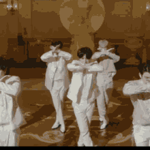 a group of men in white suits are dancing together