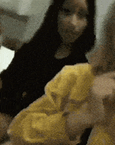a woman in a black shirt is sitting next to a woman in a yellow shirt