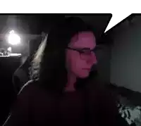 a woman wearing glasses and headphones looks at the camera in a dark room