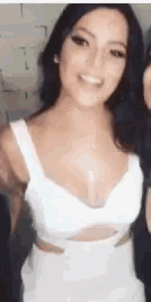 a woman in a white dress is smiling while standing next to another woman .