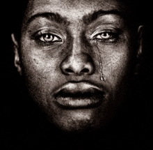 a black and white photo of a man crying with a tear running down his cheek .