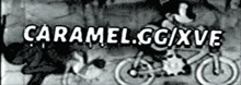 a black and white photo of mickey mouse riding a bicycle with the words caramel.cc/xve written on it