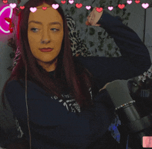 a woman wearing a blue sweatshirt with the number 15 on it flexes her arm in front of a microphone