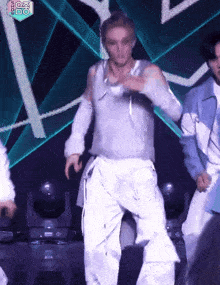 a man in a gray shirt and white pants is dancing on a stage with a fox logo in the background