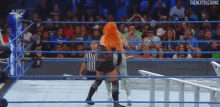 two women are wrestling in a wrestling ring with a referee .