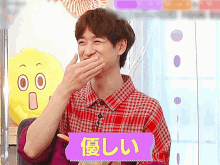 a man in a plaid shirt covering his mouth with his hand and a purple sign that says ' i ' on it