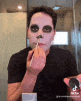 a man is applying makeup to his face with a brush and the hashtag tiktok is visible in the corner