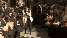 a woman in a white jacket stands in front of a crowd