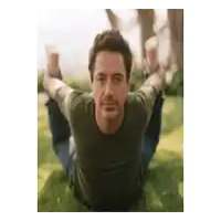a man in a green shirt is laying in the grass with his legs crossed
