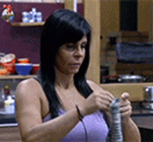 a woman in a purple tank top is holding a green object in her hands