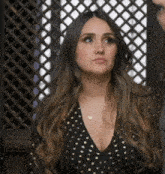 a woman in a black dress with gold polka dots is looking up