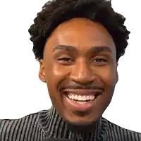 a man with curly hair and a beard is smiling and wearing a striped shirt