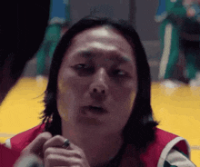 a man with long hair is holding a pen in his hand and looking at the camera .