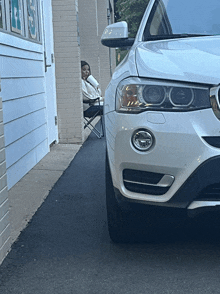 a woman sits in a folding chair next to a car