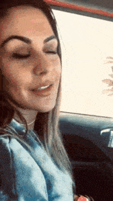 a woman is sitting in the driver 's seat of a car with her eyes closed and smiling .