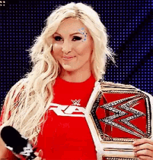 a woman in a red shirt is holding a red wrestling belt .