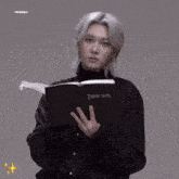 two young men are standing next to each other and one is holding a death note book