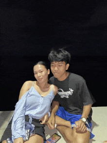 a man wearing a black shirt that says ' umbrella ' on it sits next to a woman