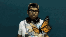 a man wearing headphones and a t-shirt that says icon holds a butterfly
