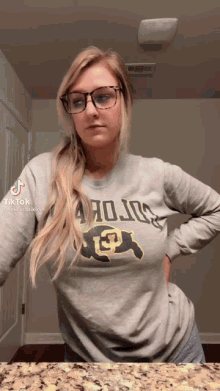 a woman wearing glasses and a shirt that says ' uc ' on it