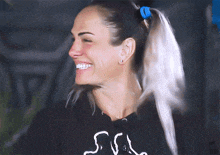 a woman wearing a black sweatshirt with the letter s on it smiles