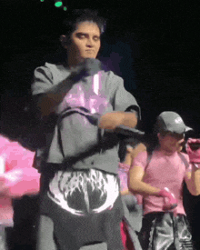 a man in a gray shirt with a skull on the back is dancing on a stage