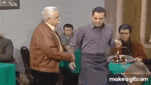 a man is holding a cake with a candle on it in front of a group of people .