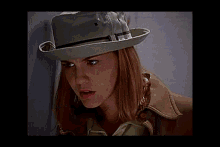 a woman with red hair is wearing a white hat and a brown coat .