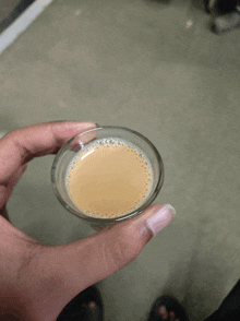 a person is holding a small glass of coffee