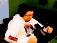 a man in a white hoodie is sitting in front of a microphone