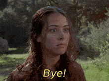 a woman says bye in front of a field