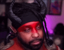 a man with red face paint and horns is wearing a headband that says someone