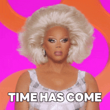 a drag queen says time has come while wearing a white dress