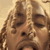 a close up of a man 's face with dreadlocks sticking his tongue out .