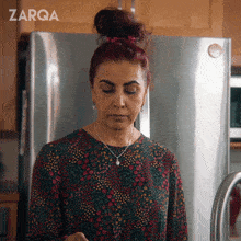 a woman is standing in front of a refrigerator with the word zarqa on the bottom