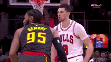 two basketball players are standing next to each other on a court . one of the players has the number 95 on his jersey .
