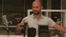 a bald man stands in front of a microphone and a box that says ' bose ' on it